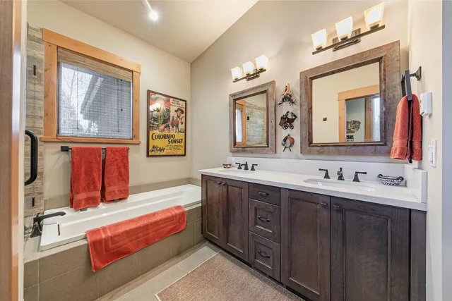 a bathroom with a tub double sink and mirror