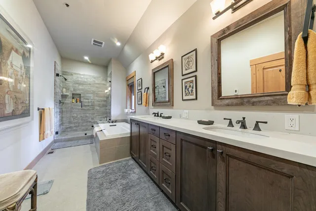 a spacious bathroom with a double vanity sink a large mirror and a bathtub