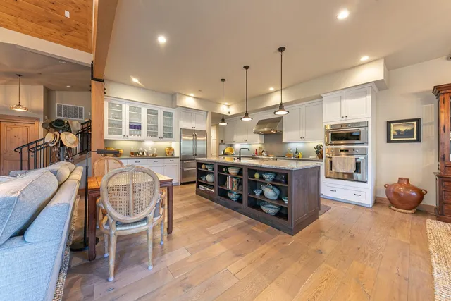 a kitchen with stainless steel appliances granite countertop a stove top oven a sink dishwasher a dining table and chairs with wooden floor