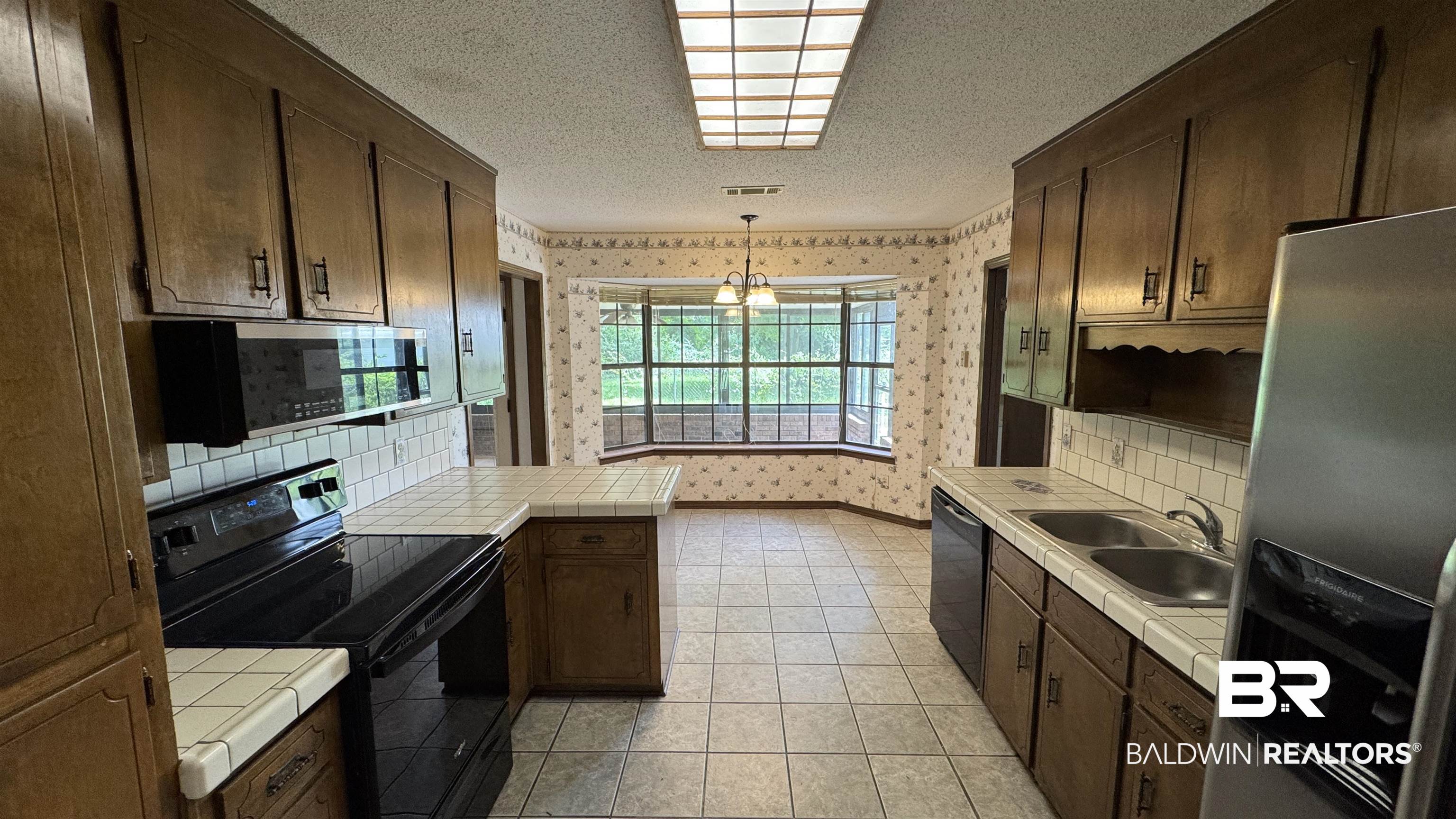 33370 Highway 98 Lillian, AL 36549 - Photo 22 of 58 Spacious kitchen featuring extensive cabinetry, tile countertops, a built-in microwave, and a double basin sink