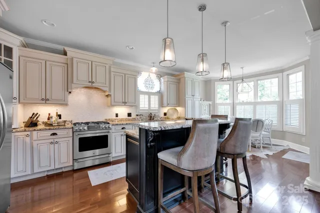 a kitchen with granite countertop a stove a sink a dining table and chairs