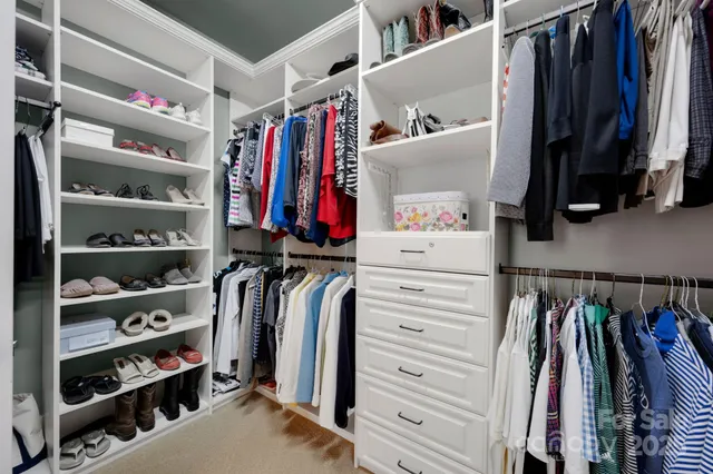 a view of walk in closet with clothes and shoes