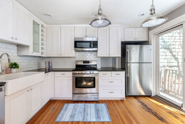 a kitchen with stainless steel appliances a refrigerator a stove a sink and white cabinets