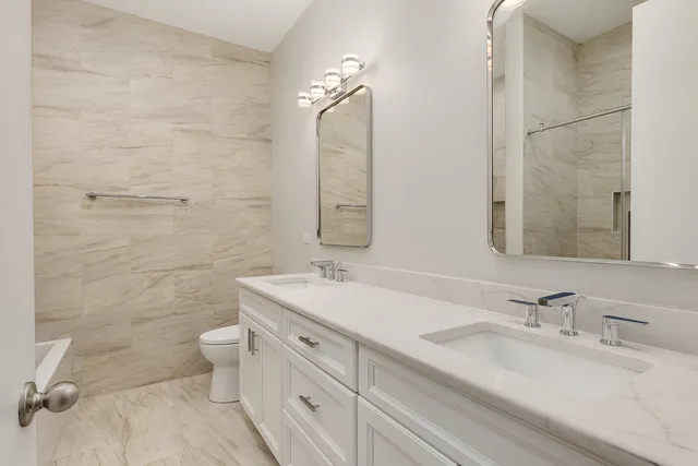 a bathroom with a double vanity sink toilet and a mirror