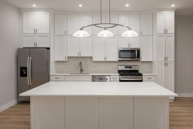 a kitchen with stainless steel appliances a refrigerator a stove a microwave and white cabinets