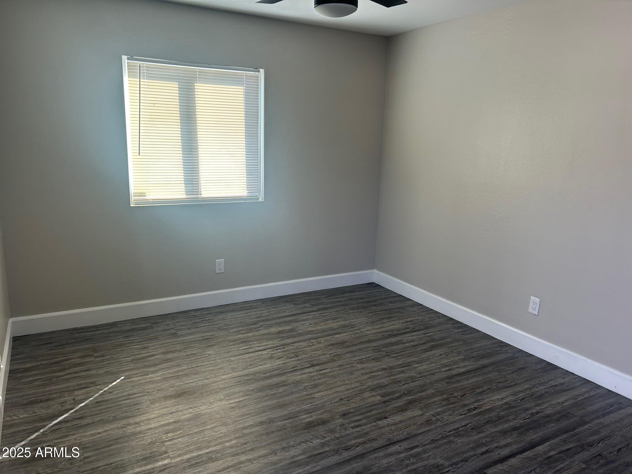 2246 West Southern Avenue, Unit 20 Phoenix, AZ 85041 - Photo 7 of 8 a view of an empty room with wooden floor and a window