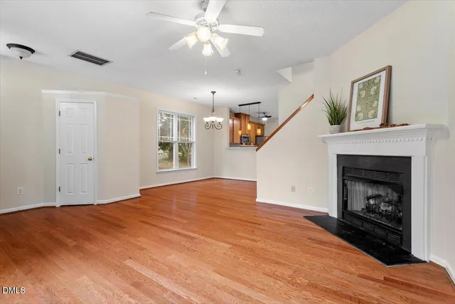 a view of a room with wooden floor a ceiling fan and windows