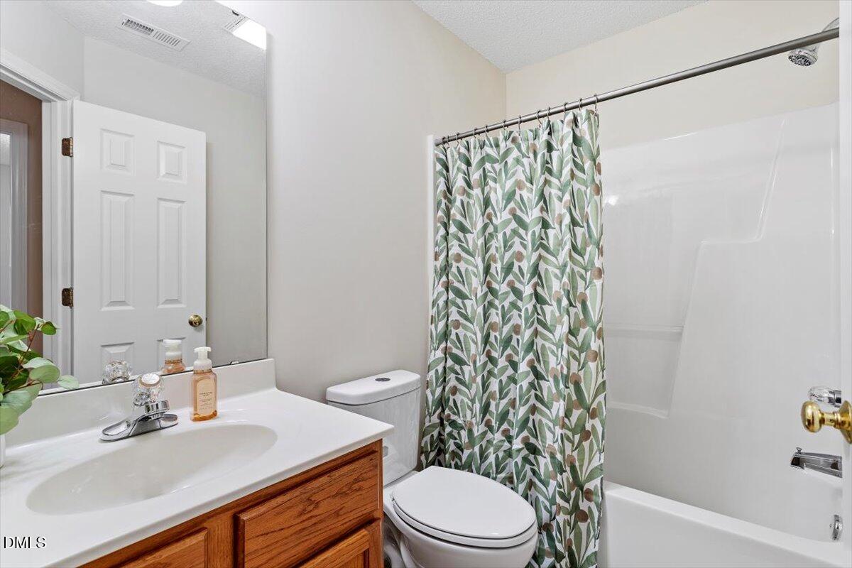 1039 Dual Parks Road Apex, NC 27502 - Photo 26 of 46 a bathroom with a sink a toilet and shower curtain