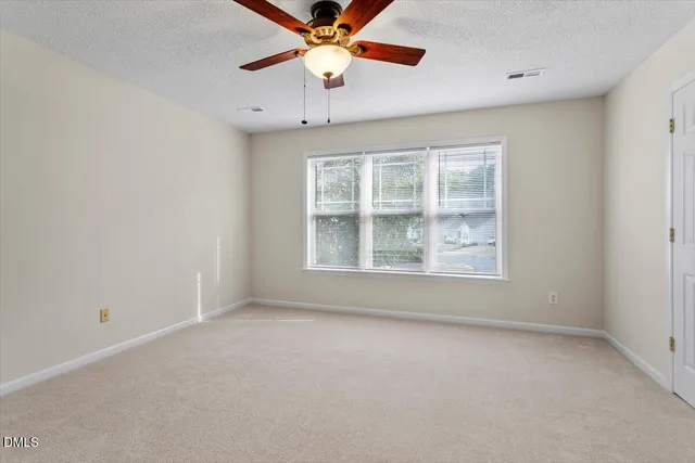 an empty room with windows and fan
