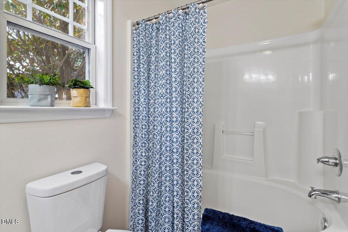 1039 Dual Parks Road Apex, NC 27502 - Photo 32 of 46 a bathroom with a toilet and a shower curtain