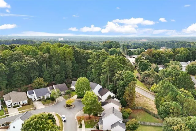 an aerial view of residential houses with outdoor space and trees