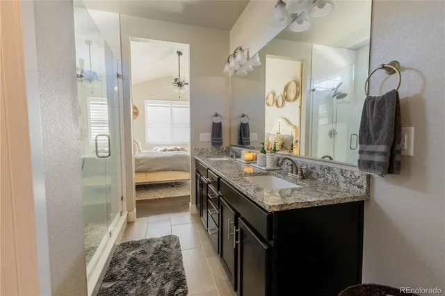 a en suite bathroom with a granite countertop sink a mirror and shower