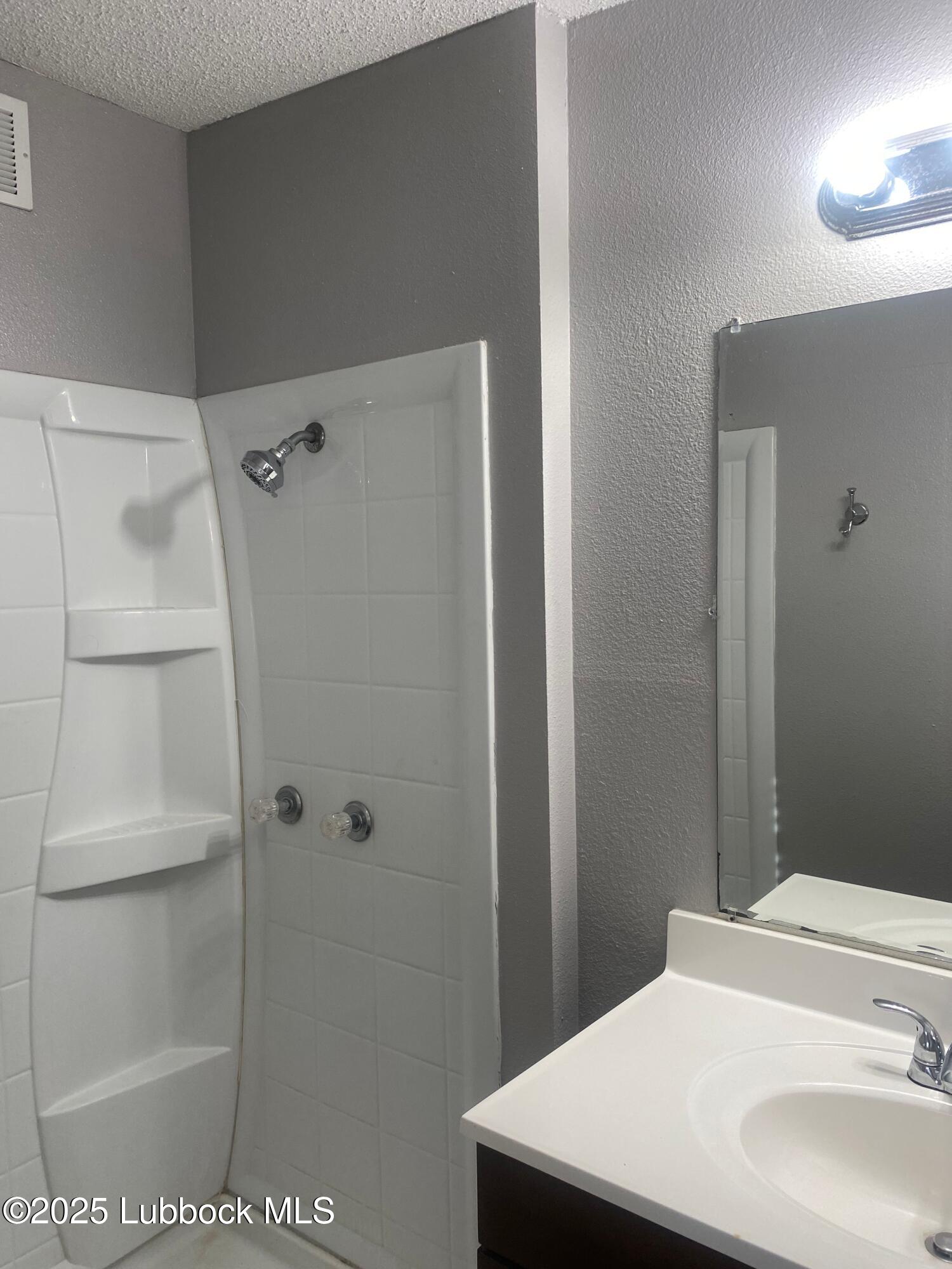 2704 68th Street Lubbock, TX 79413 - Photo 11 of 12 a bathroom with a sink a toilet and shower