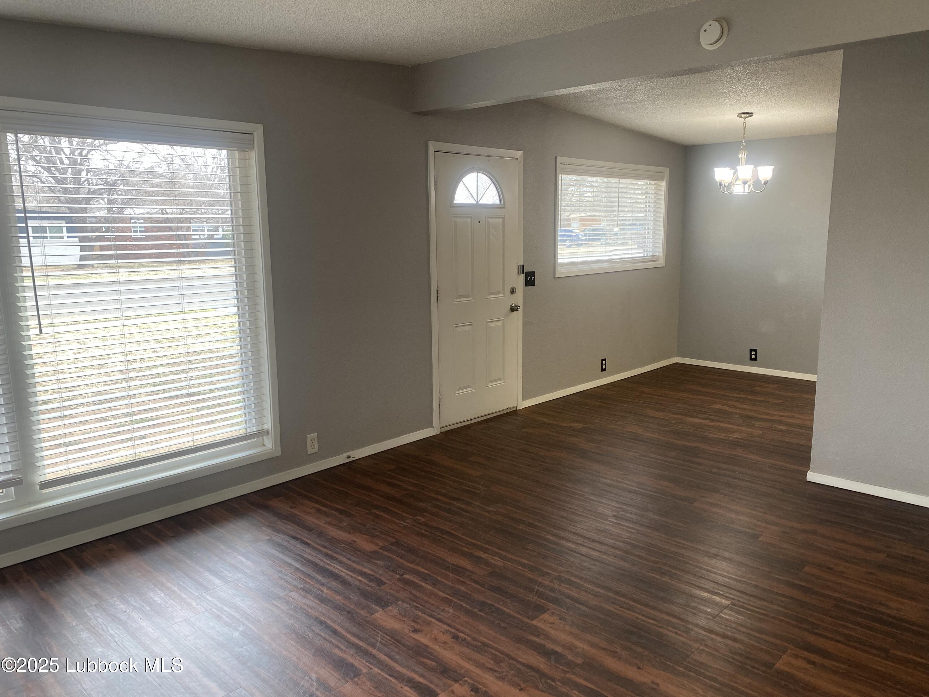 2704 68th Street Lubbock, TX 79413 - Photo 2 of 12 an empty room with wooden floor and windows
