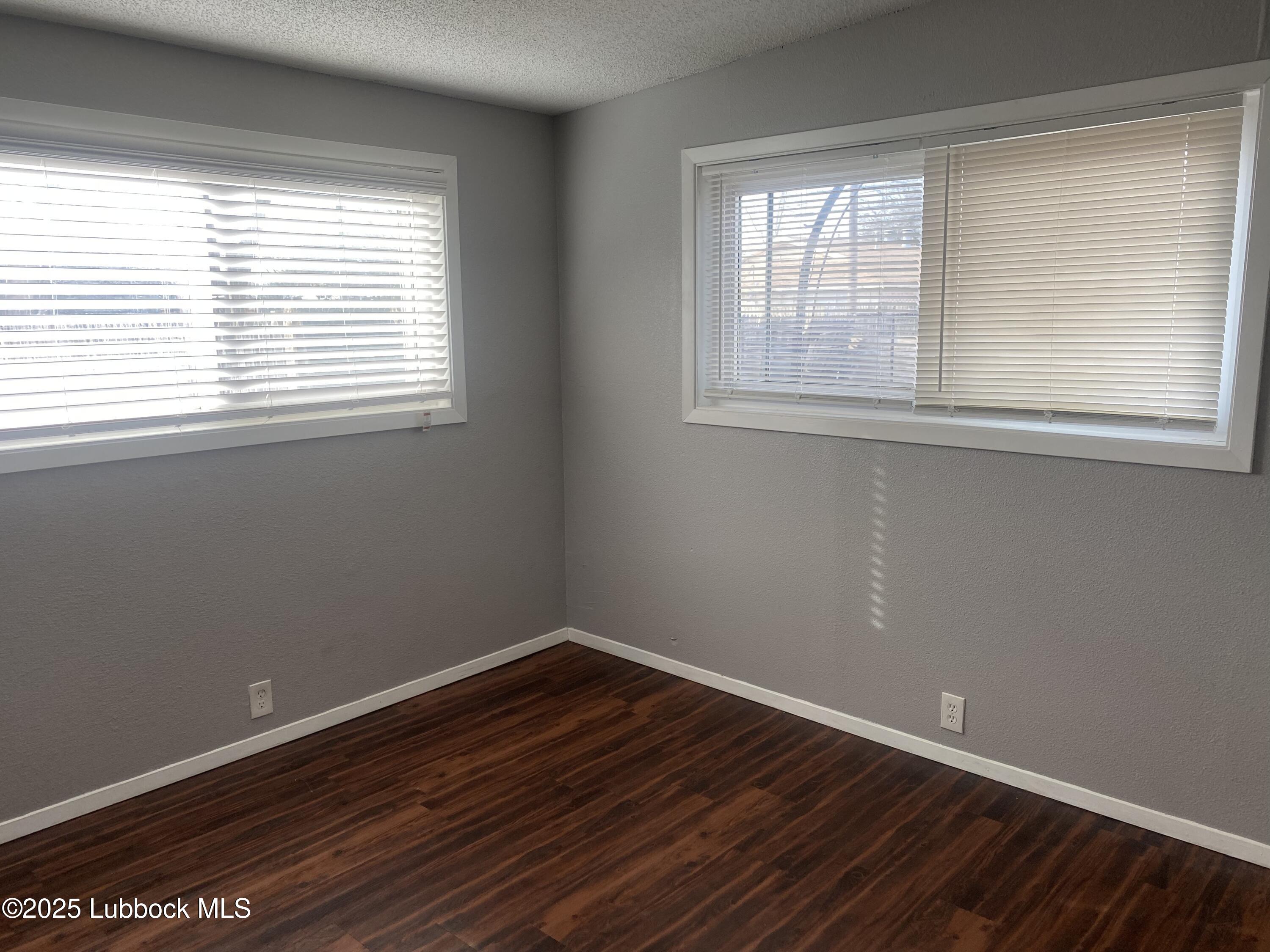2704 68th Street Lubbock, TX 79413 - Photo 6 of 12 a view of an empty room with wooden floor and a window