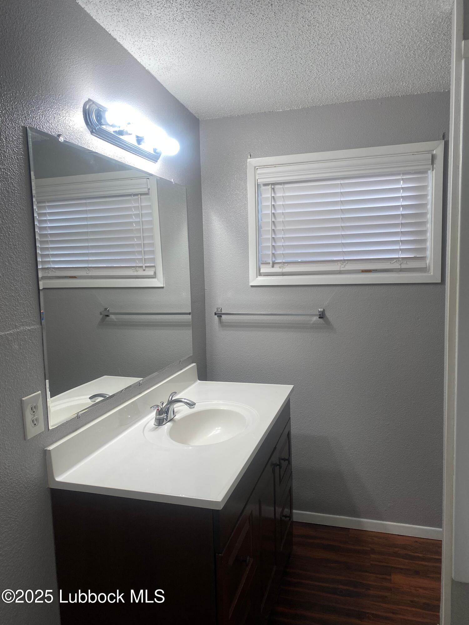 2704 68th Street Lubbock, TX 79413 - Photo 8 of 12 a bathroom with a sink a vanity and a mirror