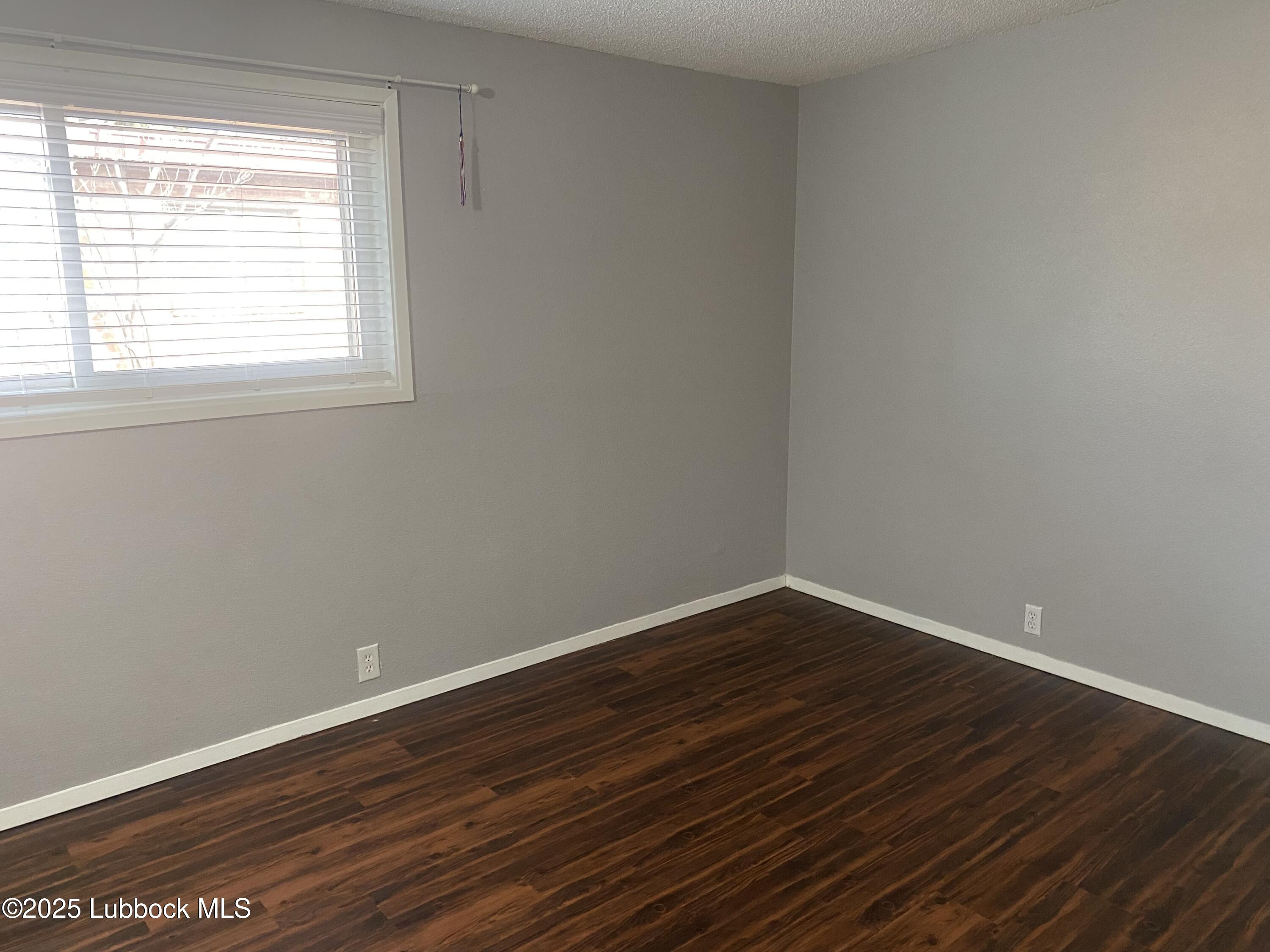 2704 68th Street Lubbock, TX 79413 - Photo 10 of 12 a view of an empty room with wooden floor and a window