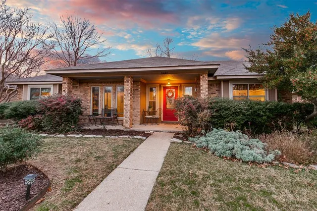 a view of a house with potted plants and a large tree
