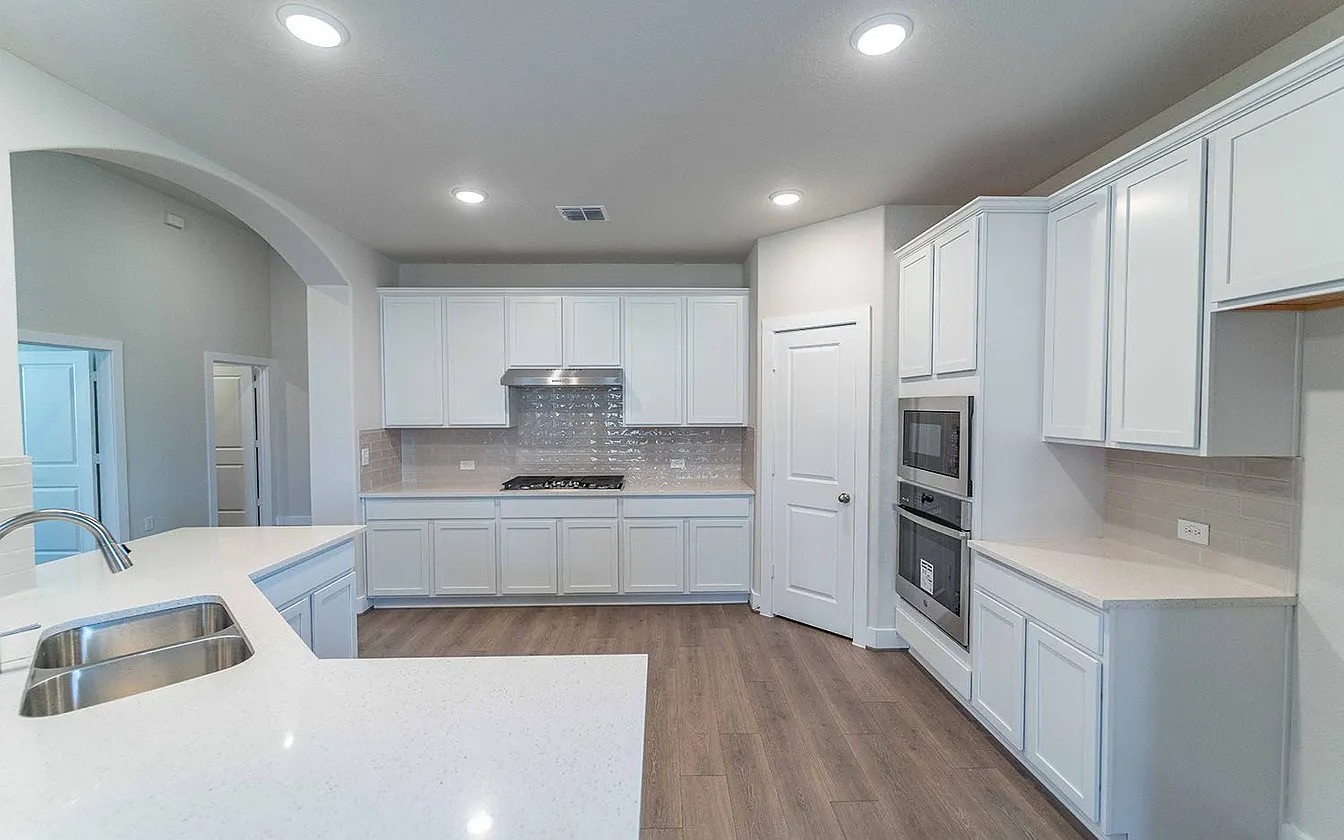 450 Durian Loop Buda, TX 78610 - Photo 3 of 17 A well-lit culinary space showcases elegant cabinetry and modern stainless steel appliances.