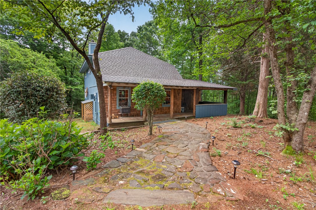 130 Maggie Rufus Lane Westminster, SC 29693 - Photo 2 of 50 A winding stone path leads through lush greenery to a charming woodland cottage.