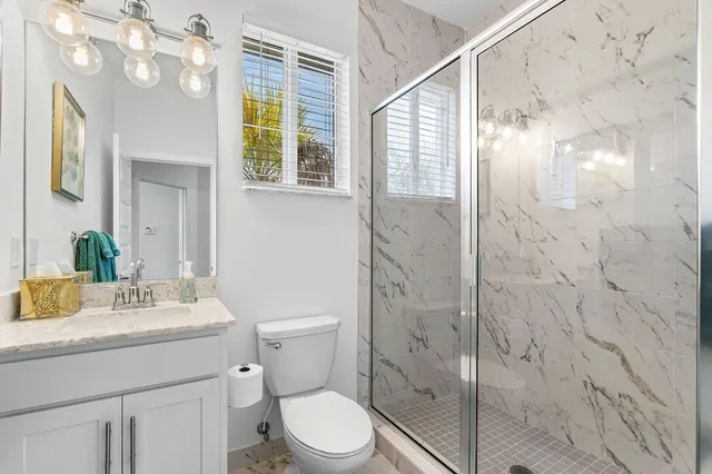 a bathroom with a sink a mirror a toilet and shower