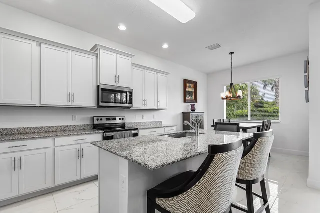 a kitchen with granite countertop sink stove and white cabinets with wooden floor