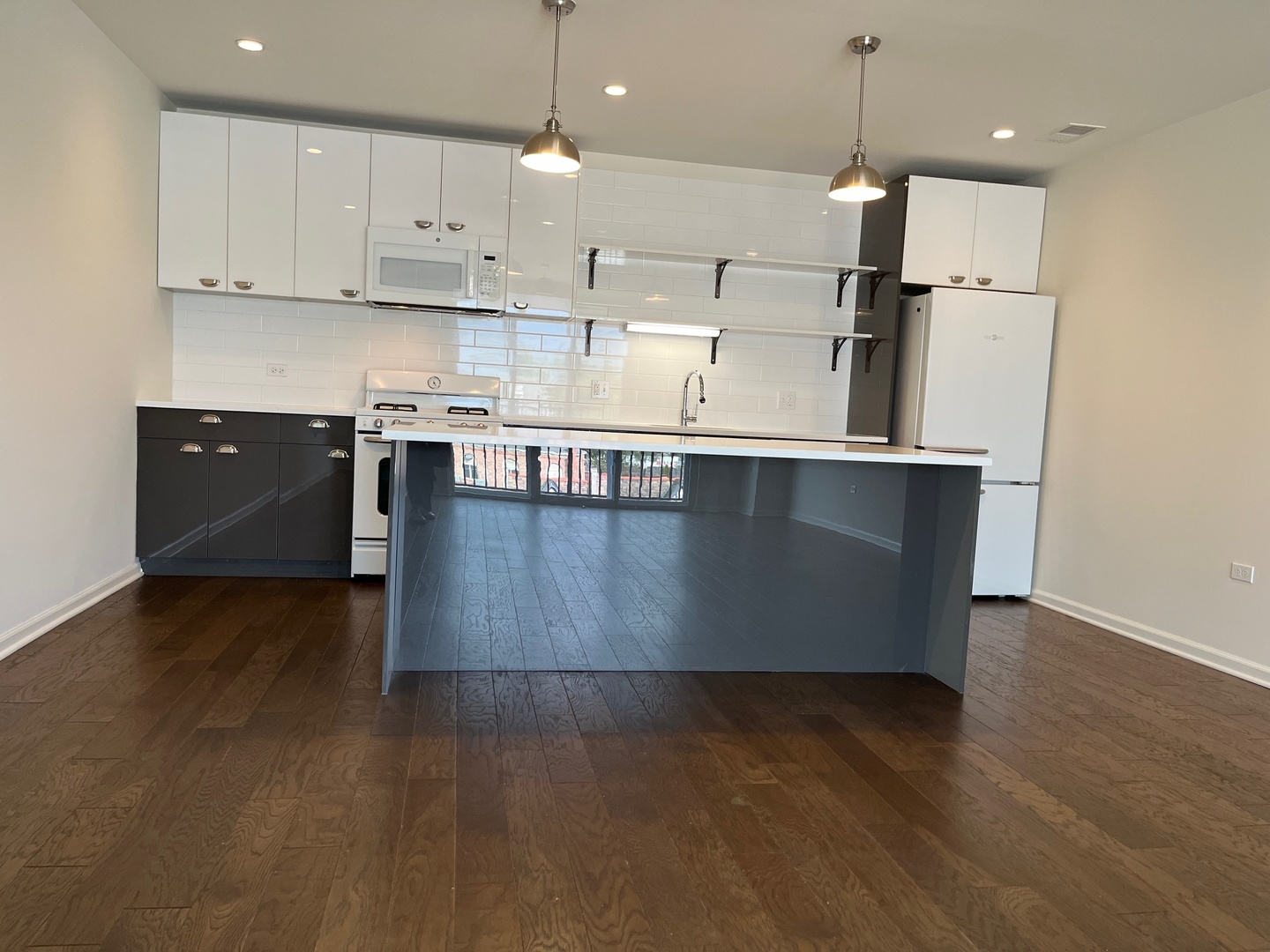 a large kitchen with stainless steel appliances granite countertop a stove a refrigerator a sink a microwave and wooden floor