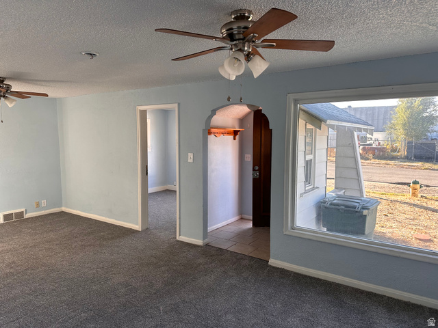 154 East Harris Street Ogden, UT 84401 - Photo 8 of 10 Empty room featuring a ceiling fan, arched walkways, a textured ceiling, and dark colored carpet