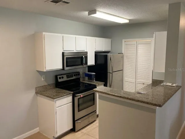 a kitchen with granite countertop a refrigerator and a sink