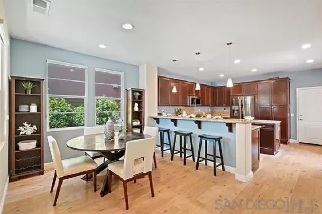 a kitchen with a dining table chairs and refrigerator