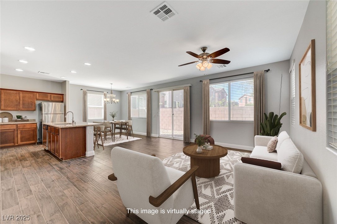 Living room with a chandelier, dark wood finished floors, ceiling fan, and recessed lighting
