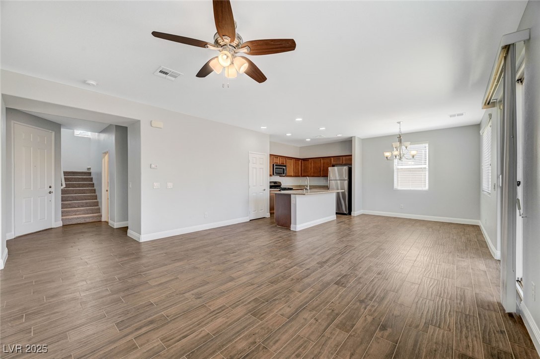5377 Panaca Spring Street Las Vegas, NV 89122 - Photo 10 of 59 Unfurnished living room featuring stairway, a ceiling fan, a chandelier, dark wood-type flooring, and recessed lighting