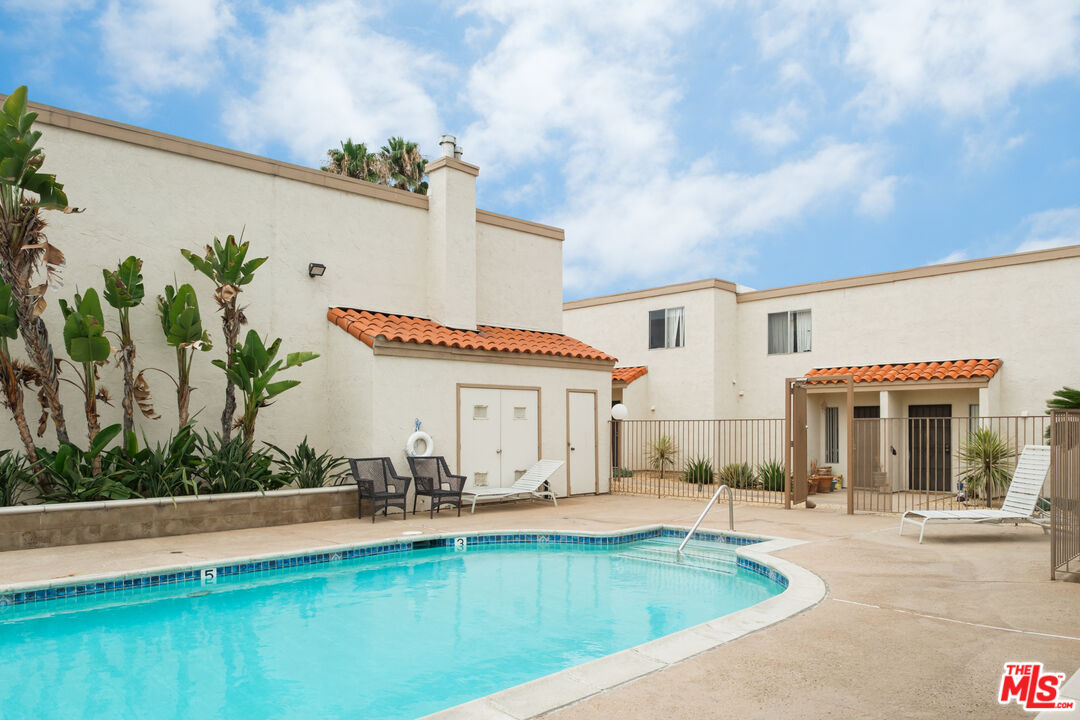 748 North 3rd Street El Cajon, CA 92021 - Photo 4 of 9 a view of a white house with a swimming pool and a lawn chairs under an umbrella