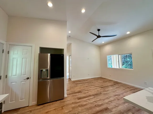 an empty room with wooden floor closet and windows