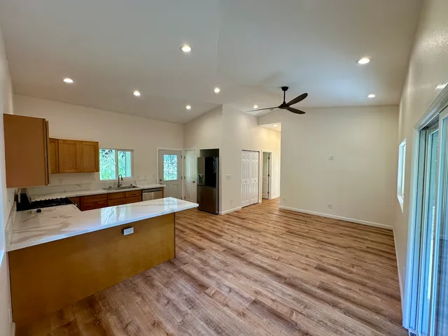 a large kitchen with stainless steel appliances a large counter top a sink and a refrigerator