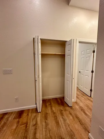 an empty room with wooden floor and entrance