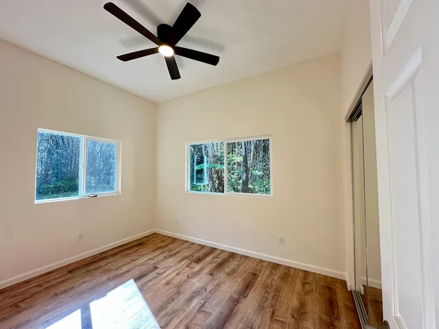 a view of empty room with wooden floor and fan