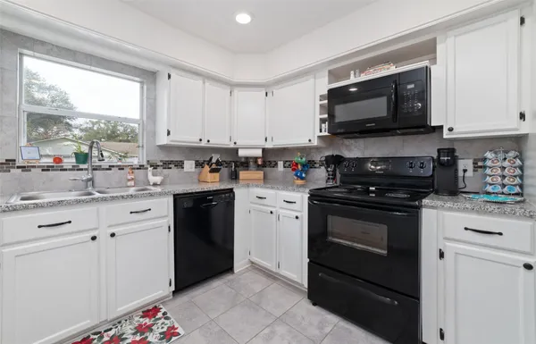 a kitchen with stainless steel appliances kitchen island granite countertop white cabinets granite counter tops a sink and a stove