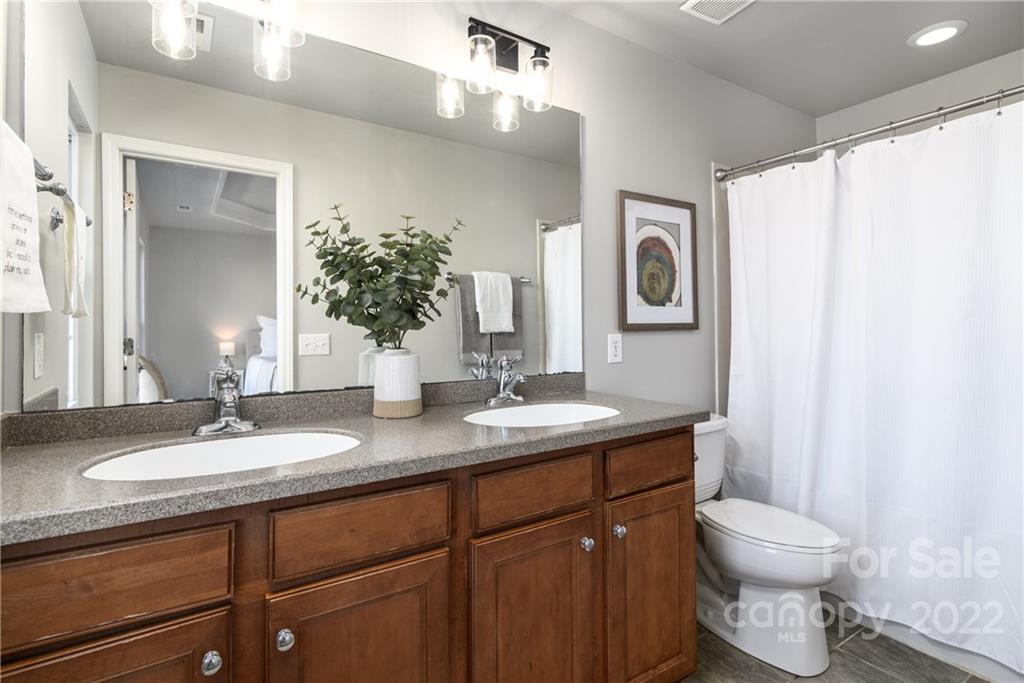669 6th Baxter Crossing Fort Mill, SC 29708 - Photo 22 of 39 a bathroom with a granite countertop sink toilet a mirror and a shower