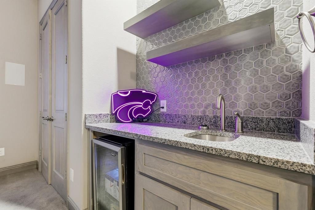 7751 Faught Road Northlake, TX 76226 - Photo 18 of 39 Wet bar with granite countertops, hexagonal tile backsplash, stainless steel sink with gooseneck faucet, custom cabinetry, and built-in beverage refrigerator