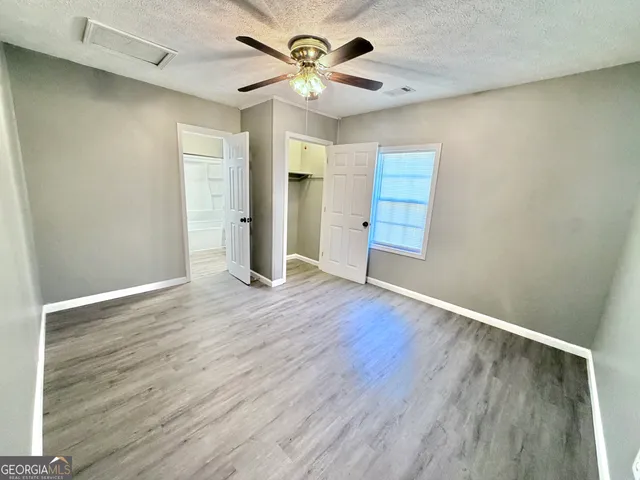 an empty room with wooden floor and a ceiling fan