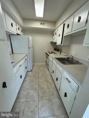 a kitchen with granite countertop a sink a stove and a refrigerator