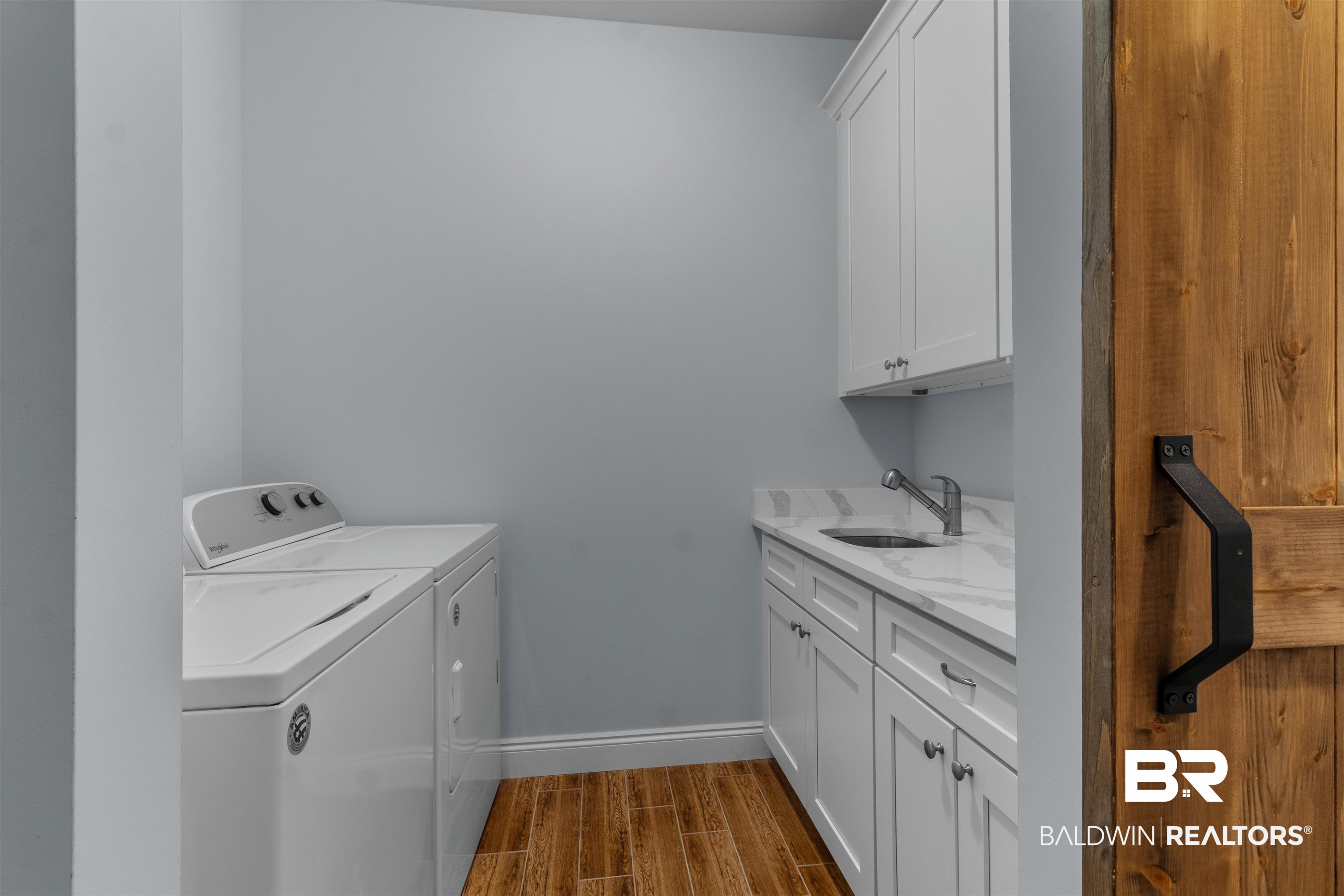 927 Periwinkle Lane Foley, AL 36535 - Photo 11 of 26 Dedicated laundry room featuring wood-finish flooring, light blue wall paint, white shaker cabinetry, and a countertop with an undermount sink