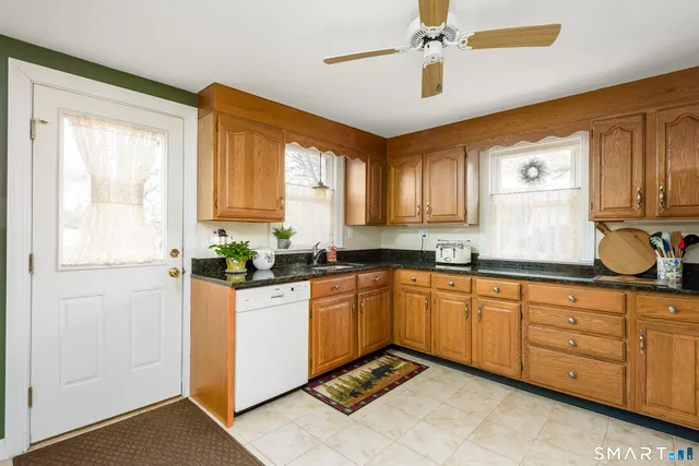 a kitchen with granite countertop a sink cabinets stainless steel appliances and a window