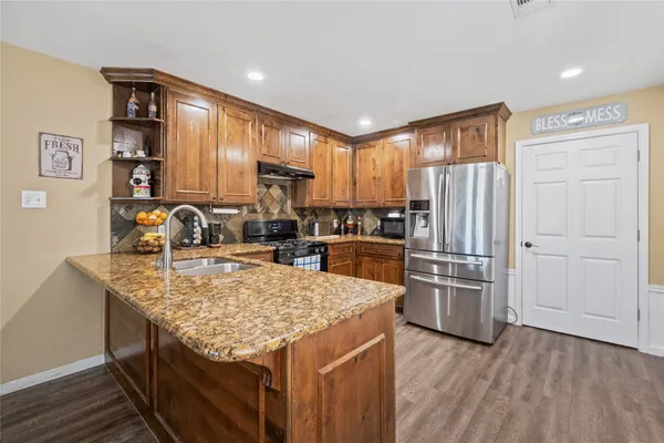 a kitchen with stainless steel appliances granite countertop a refrigerator a stove and a wooden cabinets