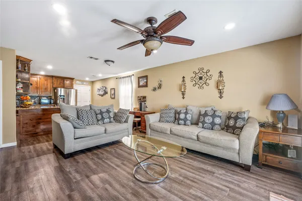 a living room with furniture a large window and wooden floor