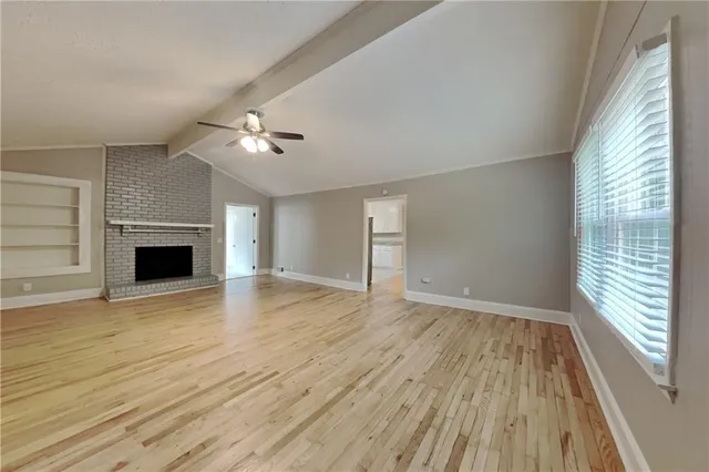 a view of empty room with wooden floor and fireplace