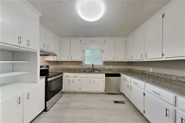 a kitchen with granite countertop white cabinets and stainless steel appliances