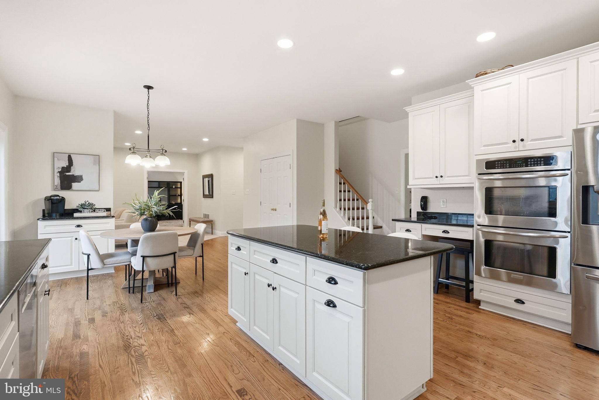 22 Springlea Lane Chester Springs, PA 19425 - Photo 22 of 80 a kitchen with stainless steel appliances kitchen island granite countertop a stove top oven a sink a dining table and chairs with wooden floor