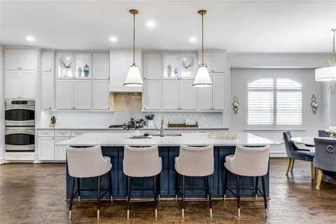 a kitchen with kitchen island granite countertop a dining table chairs and white cabinets
